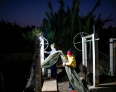 Surakit Laeaddee and his worker hold up a shrimp net at his shrimp farm in Leam Fa Pha, Thailand